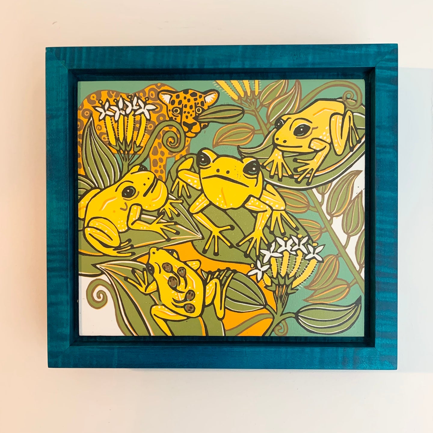 Dart frog woodcut framed in blue solid tiger maple wood
